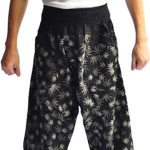 May include: Black pants with a white marijuana leaf pattern. The pants have an elastic waistband and are loose fitting.