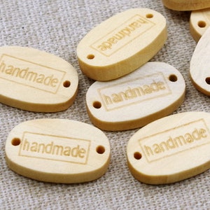 May include: Wooden oval tags with the word "handmade" engraved on them. The tags have two holes for string or ribbon.
