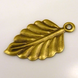 Könnte beinhalten: Ein goldfarbener Metall-Blatt-Anhänger mit einer Öse zum Anbringen an Schmuck oder andere Bastelarbeiten.