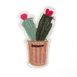 Könnte beinhalten: Eine gestickte Kaktuspflanze in einem Terrakotta-Topf mit rosa Blüten. Der Kaktus ist ein beliebtes Dekorationselement für zu Hause.