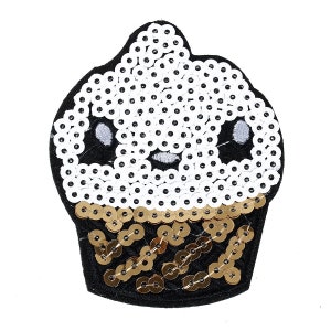 Puede incluir: Una aplicación de cupcake de lentejuelas blancas y doradas con un contorno negro y una linda carita de dibujos animados.