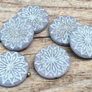 Può includere: Sei piastrelle di ceramica rotonde con un motivo a fiocco di neve bianco su uno sfondo lilla chiaro.