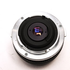 May include: A silver and black camera lens with a black lens cap. The lens has a silver ring with the text "Made in Japan" on it.