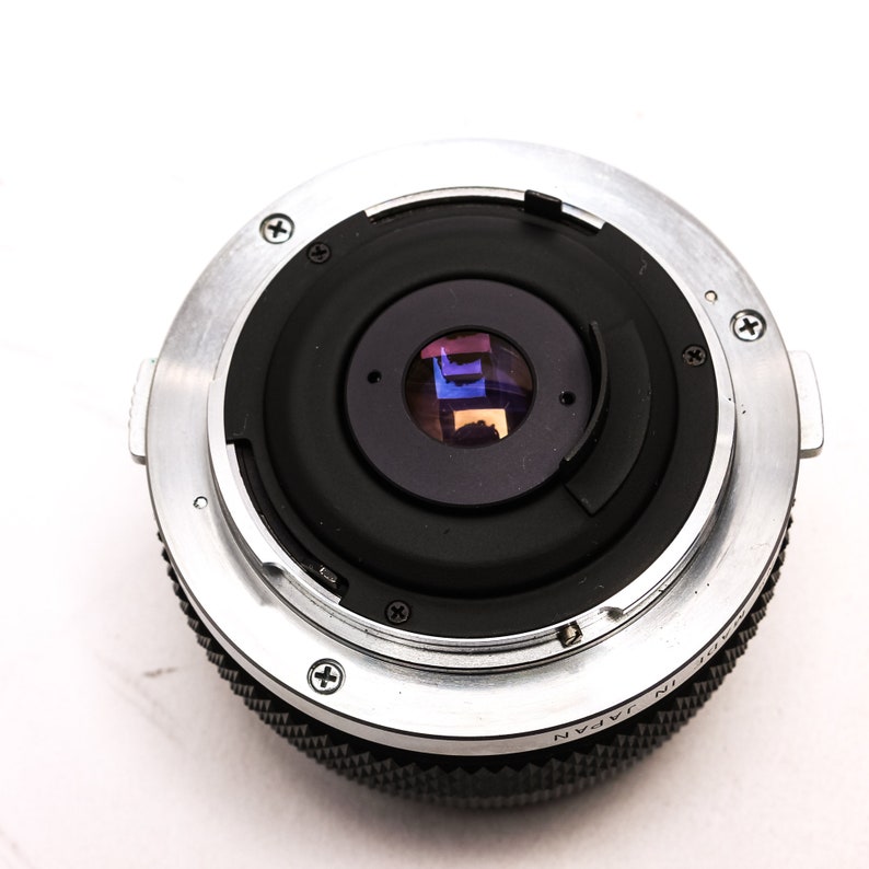 May include: A silver and black camera lens with a black lens cap. The lens has a silver ring with the text "Made in Japan" on it.