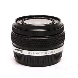 May include: A black camera lens with a silver band that reads "Lens Made in Japan".