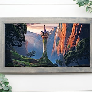 May include: A framed print of a fantasy landscape with a tall tower, a waterfall, and lush green foliage. The tower is surrounded by vines and has a small, detailed roof. The print is 10 inches by 20 inches.