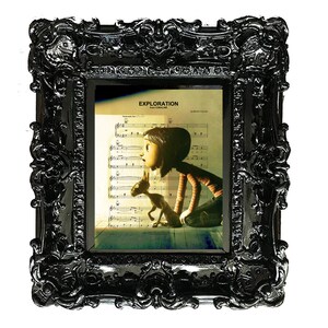 May include: A black ornate picture frame with a printed image of a girl and a small dog. The image is from the movie Coraline and the text "EXPLORATION from CORALINE" is printed at the top of the image.