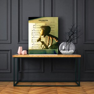 May include: A vintage-style print of a girl and a small creature looking out a window. The print is on a sheet of music with the title "EXPLORATION" at the top. The print is framed and hanging on a wall above a wooden console table.