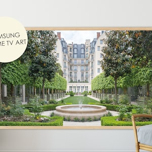 Peut inclure: Une photographie encadrée d'une cour symétrique avec une fontaine au centre. La cour est entourée d'arbres et de buissons verdoyants. Le bâtiment à l'arrière-plan est de style parisien classique avec des murs blancs et un design symétrique.