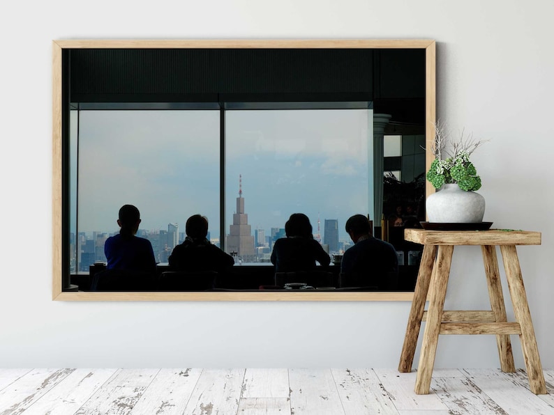 May include: A framed photograph of four people silhouetted against a city skyline, looking out a window. The city skyline includes a tall building with a radio antenna.