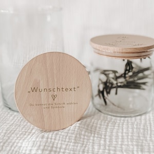 Op de afbeelding: Een houten deksel met de tekst "Wunschtext" en een hartje. Het deksel ligt op een glazen pot. De tekst onder het hartje luidt "Du kannst die Schrift wählen und Symbole".