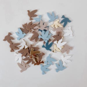 K&ouml;nnte beinhalten: Eine Sammlung kleiner, dekorativer Taubenformen in verschiedenen Blaut&ouml;nen, Braun- und Wei&szlig;t&ouml;nen. Die Tauben sind aus Acryl und haben eine gl&auml;nzende Oberfl&auml;che.