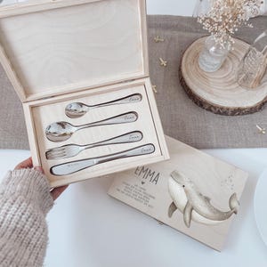 Könnte beinhalten: Ein Set aus drei Keramikbechern mit gesprenkelter, matter Oberfläche. Die Becher sind in den Farbtönen Creme, Hellgrau und Dunkelgrau gehalten. Jeder Becher hat ein schlichtes, minimalistisches Design und einen abgerundeten Henkel. Die Becher sind gestapelt.