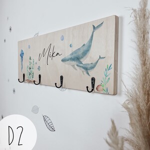 May include: Wooden coat rack with three hooks, featuring a watercolor illustration of a whale and her calf, with the name "Mikan" written on the wood.