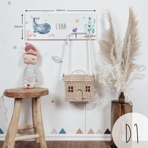 May include: White wooden coat rack with a whale, starfish, and seaweed design. The rack has two hooks and the name "LUNA" is written on it. The rack is 22 inches wide and 8 inches tall.