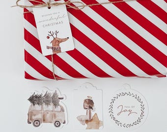 Könnte beinhalten: Vier Weihnachtsgeschenkanhänger mit Illustrationen. Ein Anhänger zeigt ein Rentier mit dem Text "Wishing you a wonderful Christmas". Ein weiterer Anhänger zeigt einen Lieferwagen mit einem Weihnachtsbaum auf dem Dach. Ein dritter Anhänger zeigt einen Engel mit einem Stern. Der letzte Anhänger zeigt einen Kranz mit dem Text "Full of Joy".