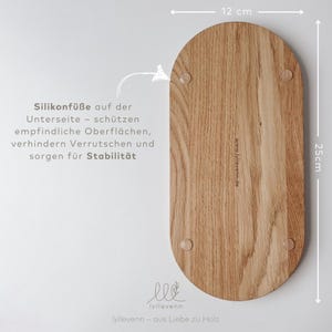 Może przedstawiać: Drewniana taca do serwowania o zaokrąglonym owalnym kształcie. Taca wykonana jest z jasnobrązowego drewna o naturalnym usłojeniu. Ma 12 cm długości i 25 cm szerokości. Taca posiada cztery małe silikonowe n&oacute;żki na spodzie, aby zapobiec ślizganiu się. Tekst "lyllevenn - aus Liebe zu Holz" jest wygrawerowany na spodzie tacy.