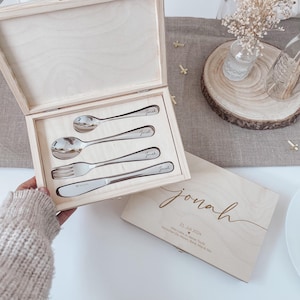 Könnte beinhalten: Ein helles Holzkästchen mit einem Besteckset. Das Set enthält einen Löffel, eine Gabel und ein Messer, die jeweils mit einem Namen graviert sind. Eine zweite Holzkiste, ebenfalls mit dem Namen "Jonah", ist sichtbar.