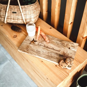 May include: A wooden serving board with the text "For you, dear Santa Claus!" engraved on it. The board is decorated with drawings of carrots, milk, and cookies. There are also two cookies on the board.