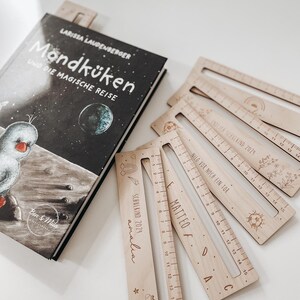 K&ouml;nnte beinhalten: Ein Set aus f&uuml;nf Holzlinealen mit personalisierten Namen und Skalierungen. Jedes Lineal hat ein einzigartiges Design, darunter ein Einhorn, ein Fu&szlig;ball, ein Regenbogen und eine Blume. Die Lineale sind aus Naturholz gefertigt und haben eine hellbraune Farbe.