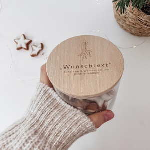 Puede incluir: Una tapa de madera para un frasco de vidrio con un diseño de muérdago y el texto "Wunschtext" "Schriften & weihnachtliche Kränze wählen".