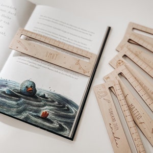 K&ouml;nnte beinhalten: Ein Set aus sieben Holzlinealen mit einem Regenbogen-, Stern- und Einhorn-Design. Die Lineale sind mit den Namen "UMUT" und "MATTEO F." sowie dem Text "SCHULKIND 2029 amalia" personalisiert.