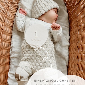 Puede incluir: Un c&iacute;rculo de madera blanco con el n&uacute;mero "1" y la palabra "MONAT" en &eacute;l. Un beb&eacute; est&aacute; acostado en una cesta de mimbre con un gorro de punto y un atuendo de punto. El texto "EINSATZM&Ouml;GLICHKEITEN" es visible en la parte inferior de la imagen.  NICHT NUR F&Uuml;R FOTOS TOLL, AUCH WUNDERSCH&Ouml;N ALS DEKO AN DER WAND. SCHNUR KANN INVIDUELL GEW&Auml;HLT WERDEN.