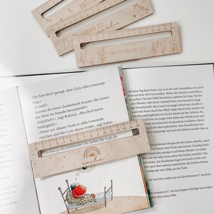 K&ouml;nnte beinhalten: Ein Holzlineal mit einem Schiebefenster f&uuml;r personalisierte Namen. Das Lineal ist mit Zahlen von 0 bis 15 gekennzeichnet. Das Lineal ist mit "emilia" beschriftet und hat eine kleine Illustration einer Sonne. Das Lineal ist ein tolles Geschenk f&uuml;r ein Kind.