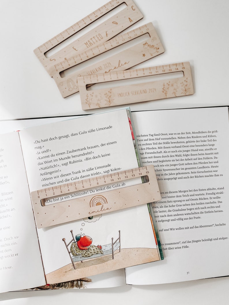 K&ouml;nnte beinhalten: Ein Holzlineal mit einem Schiebefenster f&uuml;r personalisierte Namen. Das Lineal ist mit Zahlen von 0 bis 15 gekennzeichnet. Das Lineal ist mit "emilia" beschriftet und hat eine kleine Illustration einer Sonne. Das Lineal ist ein tolles Geschenk f&uuml;r ein Kind.
