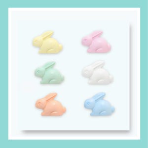 May include: A set of six small rabbit-shaped figurines arranged in two columns. The rabbits are coloured in pastel shades of yellow, pink, mint green, white, peach, and light blue. Each figurine features a smooth, matte finish and a simple silhouette.
