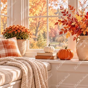 May include: A cozy window seat featuring a cream cable-knit throw blanket, a solid orange pillow, and a plaid orange and white pillow. A ceramic vase holds autumn foliage, accompanied by a white pumpkin, an orange pumpkin, and a candle.