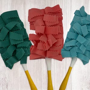 May include: Three dusters with yellow handles and white tips. The duster heads are in three colors: green, red, and teal. The duster heads are made of a soft, textured material with a scalloped edge.