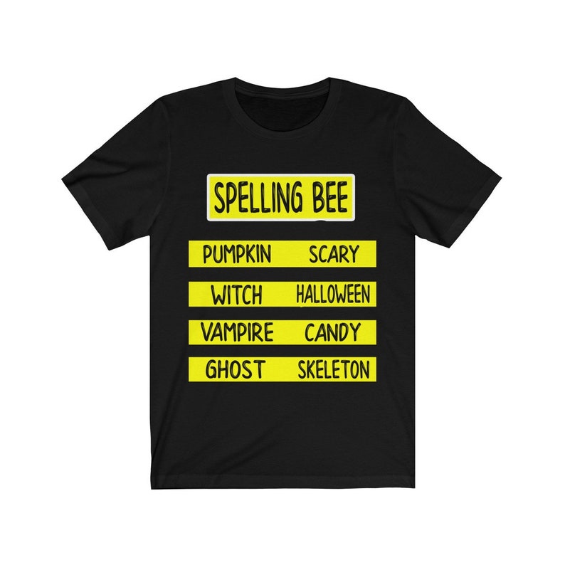 May include: Black t-shirt with a yellow sign that says "Spelling Bee" and lists Halloween words like "pumpkin", "scary", "witch", "halloween", "vampire", "candy", "ghost", and "skeleton".