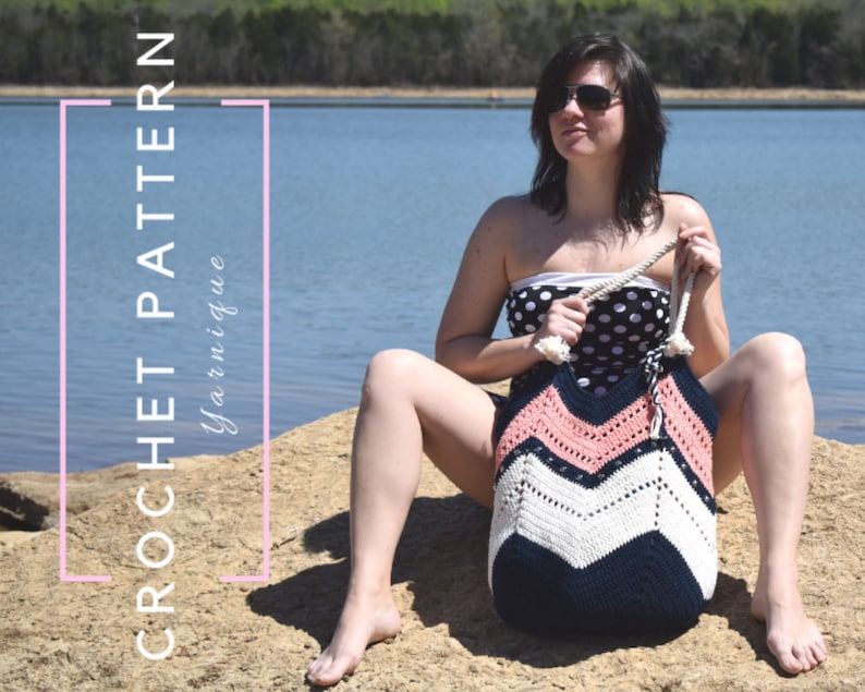 K&ouml;nnte beinhalten: Eine Frau sitzt auf einem Felsen an einem See, tr&auml;gt einen schwarz-wei&szlig;en Polka-Dot-Badeanzug und h&auml;lt eine gro&szlig;e geh&auml;kelte Tragetasche mit einem Chevron-Muster in Rosa, Wei&szlig; und Marineblau. Die Tasche hat einen Seilgriff. "CROCHET PATTERN Yarnigue" ist in Rosa auf wei&szlig;em Hintergrund geschrieben.
