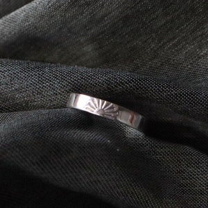 Könnte beinhalten: Ein silberner Ring mit einem Sonnenmotiv auf der Band.