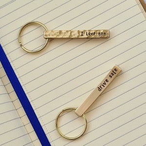 May include: Two gold keychains with a hammered metal finish. One keychain has the text "I love you" and the other has the text "drive safe".