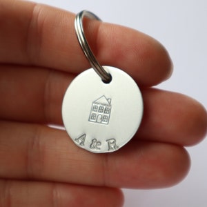 May include: Silver keychain with a house design and the initials "A & R" engraved on a round tag.