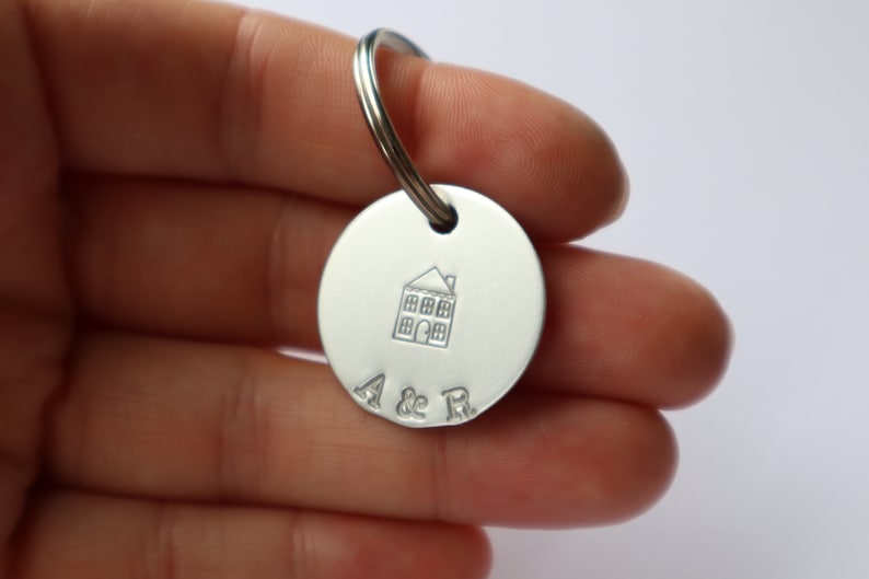 May include: Silver keychain with a house design and the initials "A & R" engraved on a round tag.