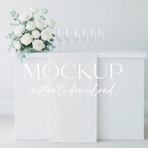 Könnte beinhalten: Eine weiße Bar mit sechs Sektgläsern und einem Strauß weißer Rosen. Die Bar hat einen weißen Stoff, der über die Vorderseite drapiert ist, mit den Worten "MOCKUP instant download" in weißer Schrift.