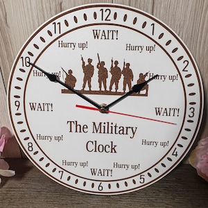 May include: A white round clock with brown numbers and text. The clock face features a line of soldiers with the text "The Military Clock". The clock hands are black and red.