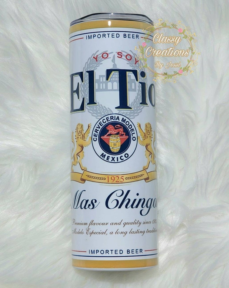 May include: A white and yellow insulated tumbler with a design of a beer can. The can features the text "El Tio" and "Mas Chingon" with a logo for Cerveceria Modelo. The text "Imported Beer" appears twice on the tumbler.