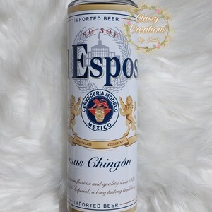 May include: A white and gold can with a blue logo that says "Espos" and "Cerveceria Modelo" with a lion on each side. The can also says "Imported Beer" and "Mas Chingon" with a description of the beer's flavor and quality.
