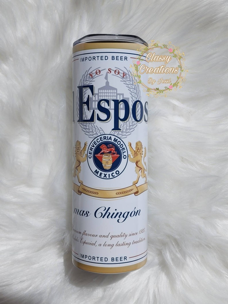 May include: A white and gold can with a blue logo that says "Espos" and "Cerveceria Modelo" with a lion on each side. The can also says "Imported Beer" and "Mas Chingon" with a description of the beer's flavor and quality.