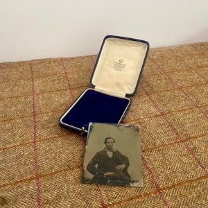 May include: A vintage photograph of a man in a dark suit and bow tie, sitting in a chair. The photo is in a blue velvet lined box with a white label that reads "Greenwood Bros. & Co. Ltd.  Manufacturing Jewellers.  London."