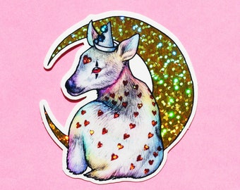 May include: A colorful, iridescent sticker of a deer wearing a crown, with a gold glitter crescent moon behind it. The deer is covered in small red hearts.