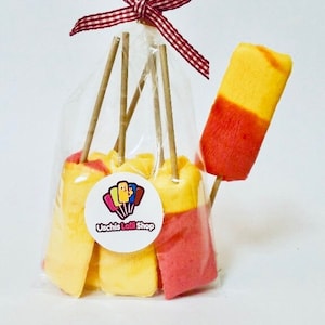 Könnte beinhalten: Eine Tüte mit gelben und roten Lollies auf Stielen. Die Lollies sind in einer durchsichtigen Plastiktüte mit einem rot-weiß karierten Band verpackt. Die Tüte hat einen Aufkleber mit dem Text "Uschis Lolli Shop".