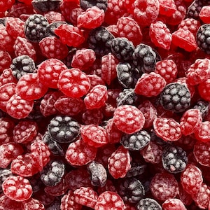 Könnte beinhalten: Nahaufnahme einer Auswahl an roten und schwarzen Süßigkeiten. Die Süßigkeiten sind mit einem weißen Zuckerguss überzogen und scheinen eine Mischung aus verschiedenen Geschmacksrichtungen zu sein.