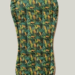 Könnte beinhalten: Ein grünes und goldenes Hochstuhlkissen mit einem Dschungel-Druck mit Leoparden und Blättern.