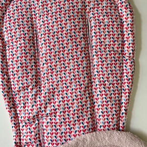 Może przedstawiać: Biało-czerwono-niebieski podnóżek do krzesełka dla dziecka z miękką, beżową podszewką z polaru.