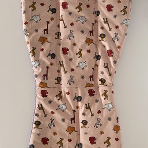 Può includere: Coprisedia per seggiolone rosa con un motivo di giraffe, elefanti, zebre e leoni. La copertura ha una cerniera sul retro.